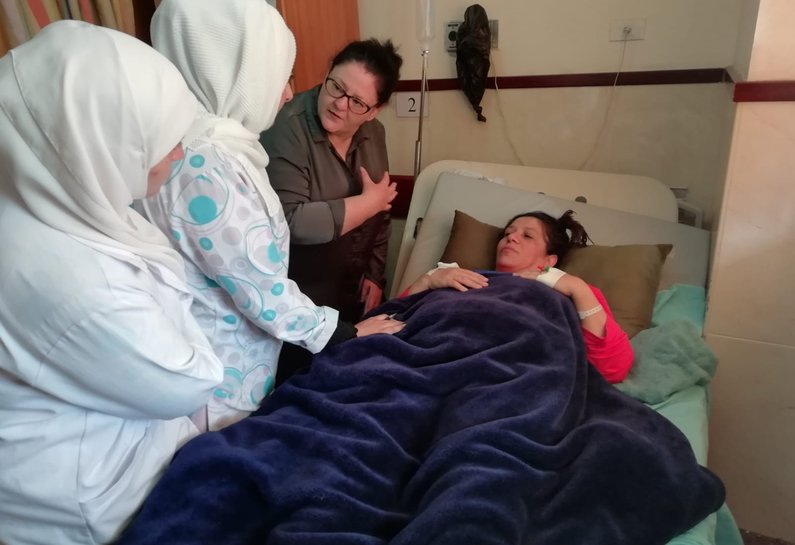 Specialist breast cancer nurse Michelle Johnson advises a patient post breast  surgery on physio techniques, during the post operative ward round at Rafidia hospital