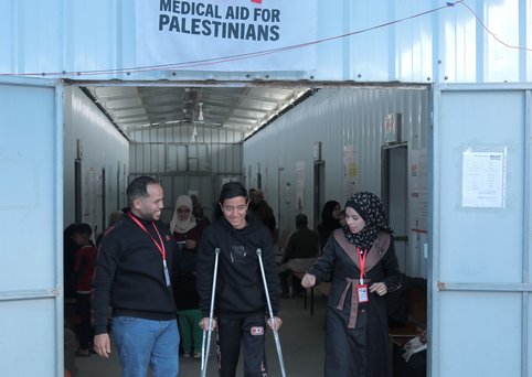 A young man walking on crutches in front of MAP signage