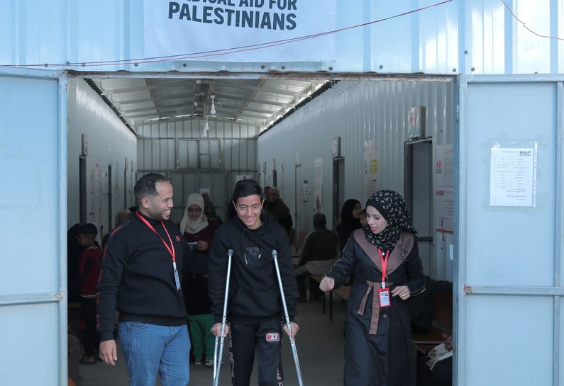 A young man walking on crutches in front of MAP signage