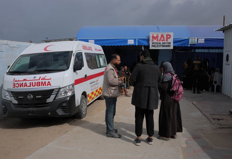 People talking at the Polyclinic with an ambulance in the background