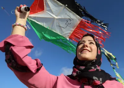 A Palestinian woman flies a kite on Gaza's coastline, June 2021.