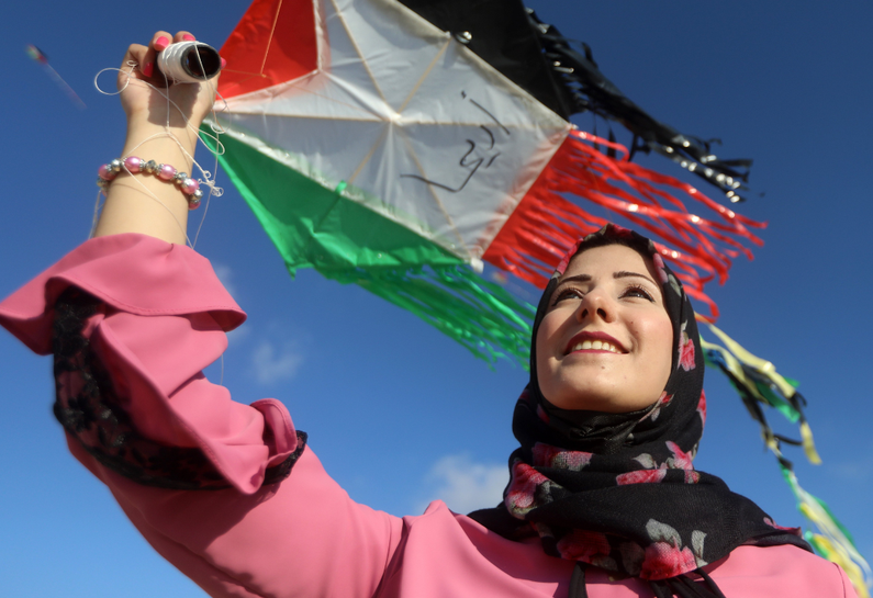 A Palestinian woman flies a kite on Gaza's coastline, June 2021.