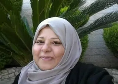 Iktimal, a Palestinian woman wearing a light grey hijab and black jacket. She smiles warmly at the camera.