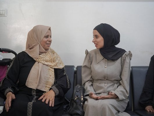two women sit chatting in a waiting room