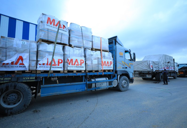 A lorry transporting pallets of aid with Medical Aid for Palestinians logo on the side.