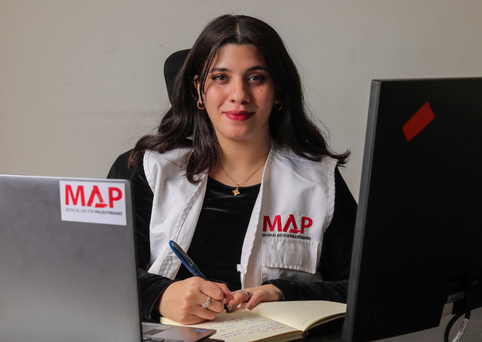 Abeer, MAP Medical Coordinator, sitting at her desk, looking at the camera with a smile.