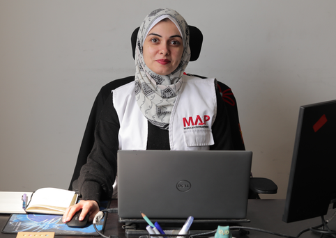 Norhan, MAP Programme Officer, sitting at her desk, looking at the camera with a smile.