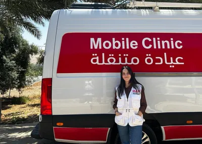 Taline standing in front of a MAP Mobile Clinic in the Jordan Valley, smiling.
