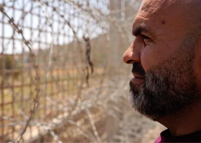 Dr. Motaz standing in front of the fence installed by the Israeli forces, which has enclosed the town of Sinjil.