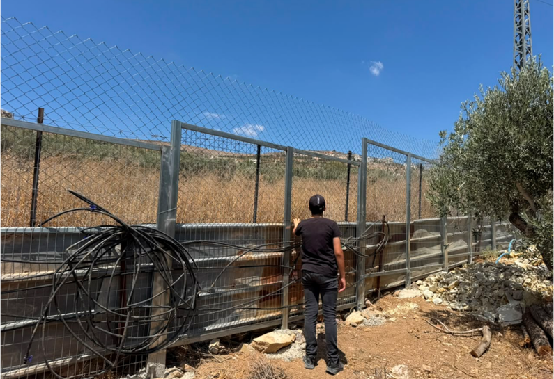 A family member standing inside Hani's house, in front of the new fences installed to protect his family from Israeli settler attacks.