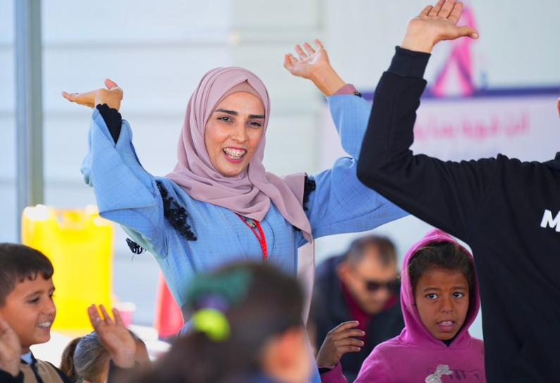 Photo of Hannan Al-Habibi, MAP Psychosocial Support Facilitator, leading an activity with children at MAP's Solidarity Polyclinic in Deir Al Balah.