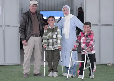 Photo of Yaqoub and Murad with their aunt, Abeer, and grandfather, Sobhi, at MAP's Solidarity Polyclinic in Deir al-Balah.