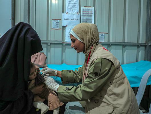 Zaina Al-Ghalayini, Community Health Worker at the Solidarity Polyclinic in Gaza checking up on a small child.
